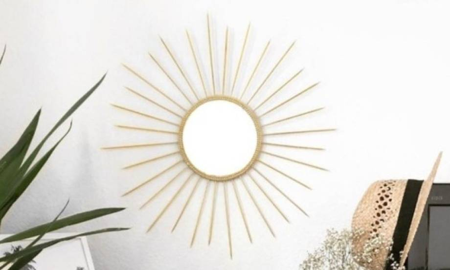 Final DIY gold sun mirror displayed on a wall with decorative skewers surrounding a round central mirror.