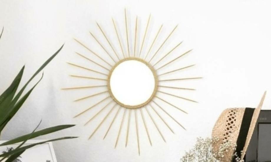 Final DIY gold sun mirror displayed on a wall with decorative skewers surrounding a round central mirror.