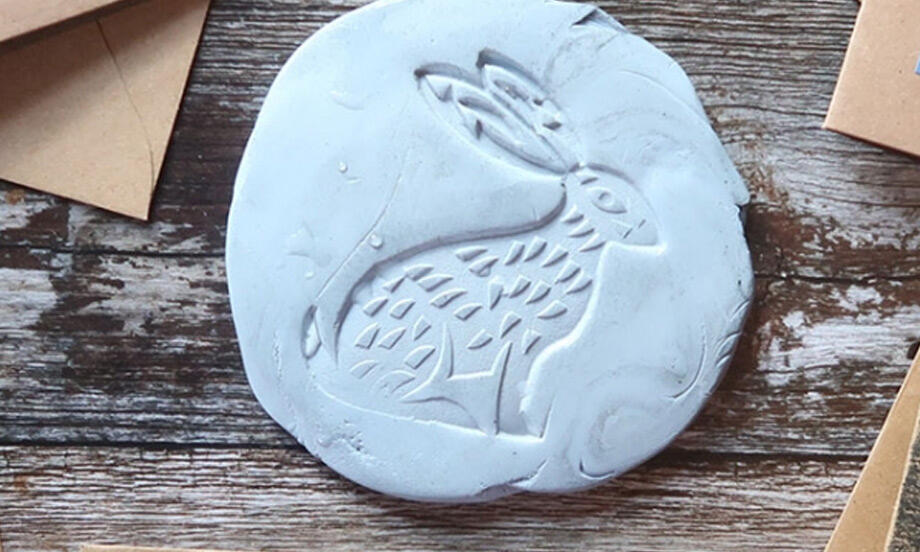 DIY reverse print of a hare design made with a carved stamp and clay impression, alongside finished prints on paper.