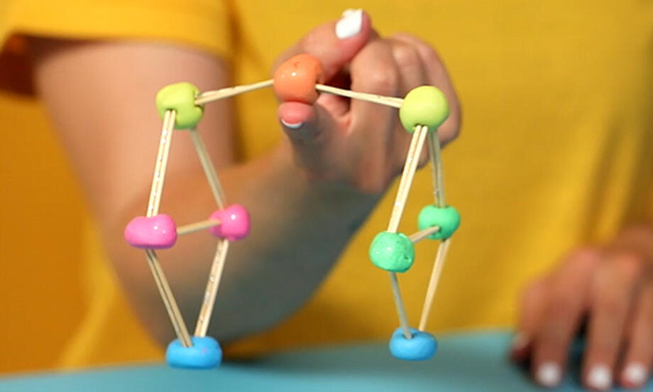 彩色黏土與木棒組成的立體平衡結構輕巧停在手指上方，展現趣味物理與手作創意結合的過程，強調幼兒 DIY 活動中探索重心與平衡的樂趣，營造寓教於樂的科學挑戰氛圍。