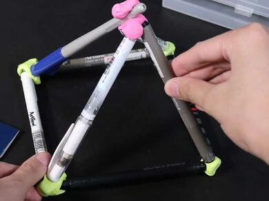 A finished pen pyramid held together with Blu Tack, shown alongside a pack of Bostik Blu Tack Colour.