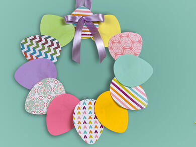 A bright and colourful Easter garland made of patterned paper eggs and a shiny purple bow, ready to decorate your space!