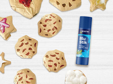 A playful display of handmade “smart cookies” decorated with colourful paper and cotton, alongside a Bostik Blu Stik glue stick.