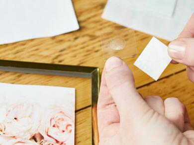Hands peeling Glu Dots from the backing sheet for use in a scrapbook.