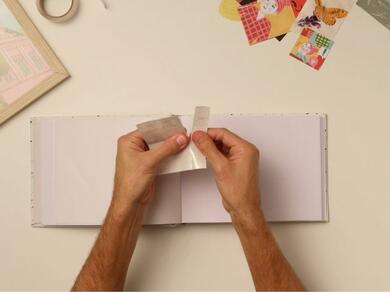 A scrapbook being decorated with cut-out images and Glu Dots.
