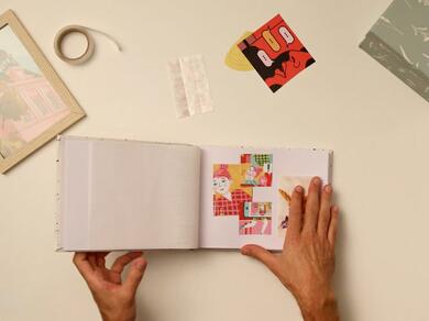 A scrapbook being decorated with cut-out images and Glu Dots.