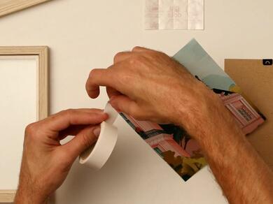 Hands applying Glu Dots to the back of a printed photo for mounting.