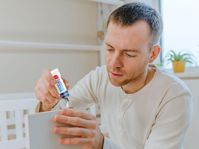 Man applying Bostik Super Glue Liquid to fix a wooden surface at home.