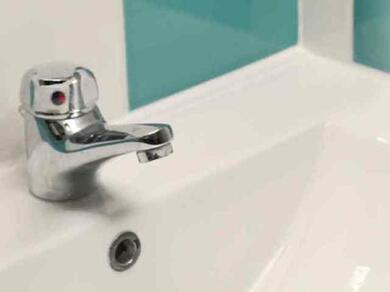 Weiße Waschbecken‑Ecke mit Armatur und offenem Fugenbereich vor türkisfarbener Fliese, ideal vorbereitet für frische, wasserfeste Silikonabdichtung im Bad.