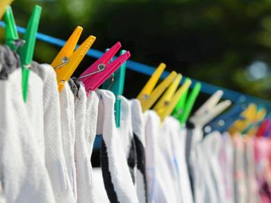 Drying laundry outdoors: A row of colourful pegs holding freshly washed clothes on a washing line in the sun.