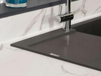 Pia de cozinha moderna com bancada de mármore branco e cuba preta, pronta para aplicação de selante para vedação.