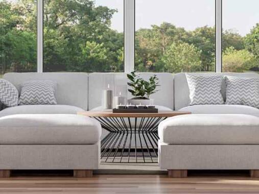 Bright, modern living room with large windows, houseplants, and natural light — symbolising home protection and comfort