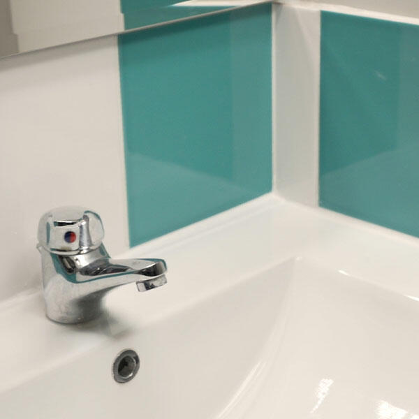 Sauber geglättete Silikonfuge am Waschbecken vor türkisfarbener Fliese, zeigt ein gleichmäßiges, wasserdichtes Ergebnis für dauerhafte Hygiene im Bad.