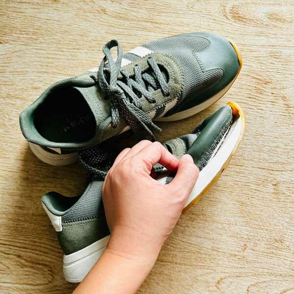 A person holding a sneaker with a detached sole, preparing it for repair.