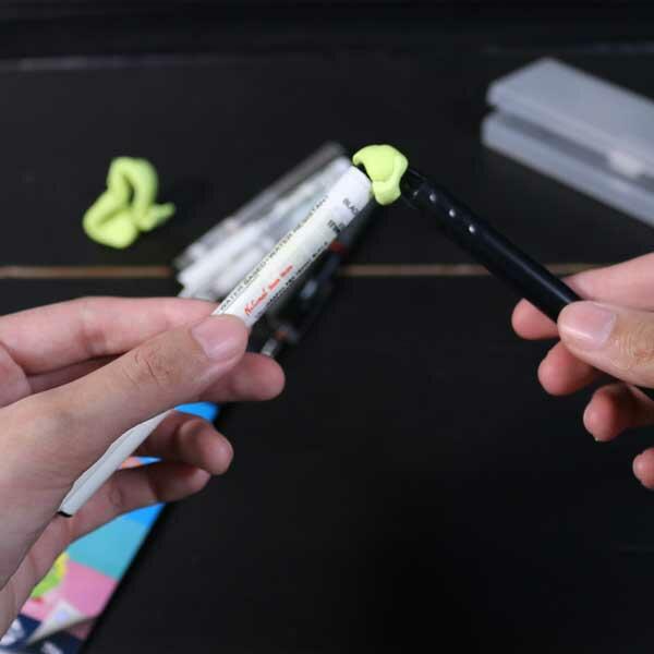 Two pens being joined at the tip with a piece of yellow Blu Tack.