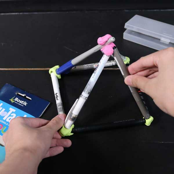 A finished pen pyramid held together with Blu Tack, shown alongside a pack of Bostik Blu Tack Colour.