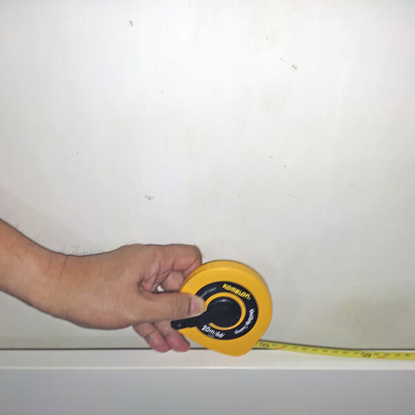 A person measuring the width of the headboard space with a tape measure.