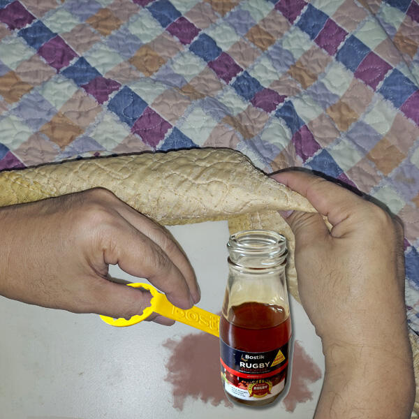 Hands applying Bostik Rugby adhesive to the back of the patterned fabric.