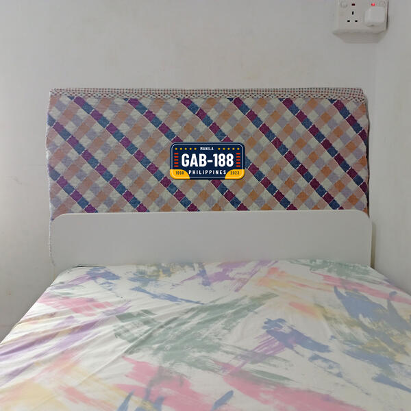 A completed personalized headboard with colourful patterned fabric and a decorative license plate design in the center.