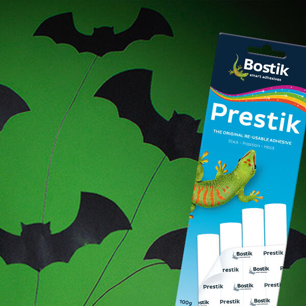 A green background with black paper bats attached using Bostik Prestik, alongside a pack of Bostik Prestik on the right side.