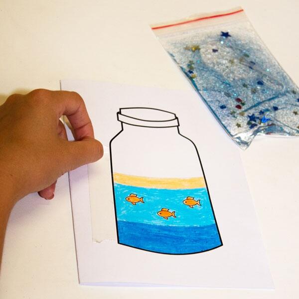 Coloured jar page being placed underneath the filled glitter bag, ready for the next crafty step.
