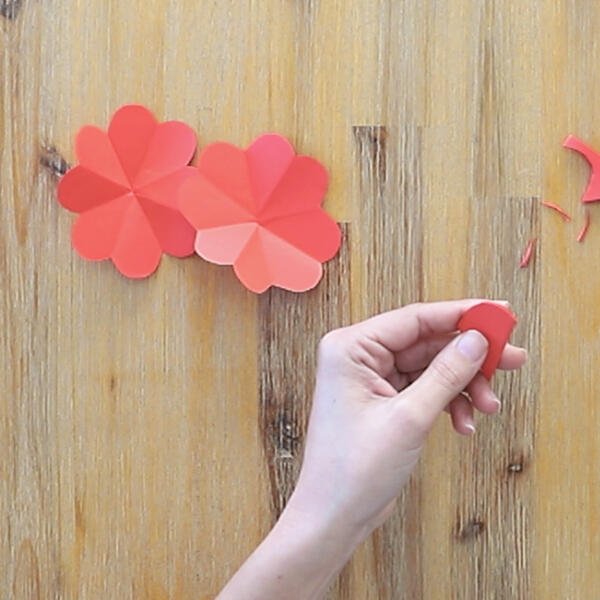 Holding a cut red petal segment after trimming the drawn shape.