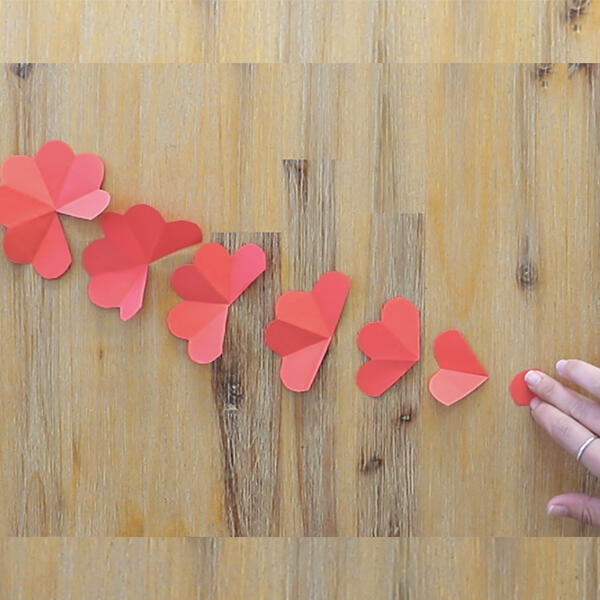 Laying out all the red paper petal pieces from largest to smallest on a wooden table.