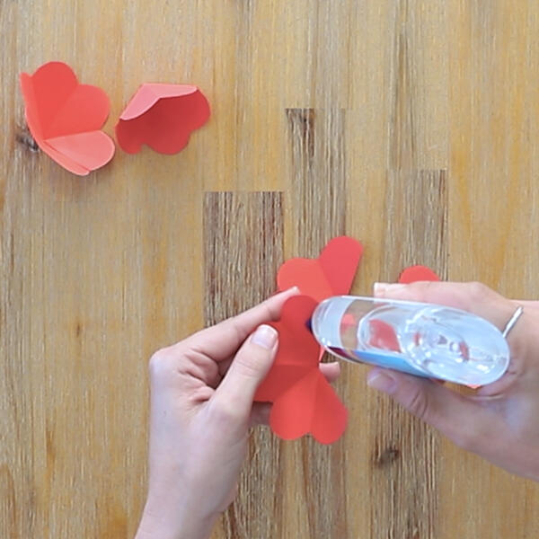 Applying Bostik Paper Glue to the centre of a red paper petal piece.