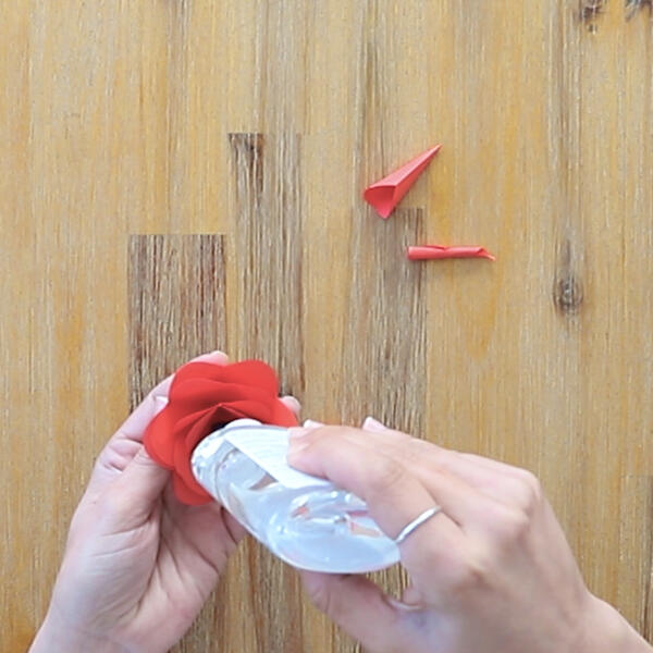 Gluing the curled paper petals together to form the rose shape.