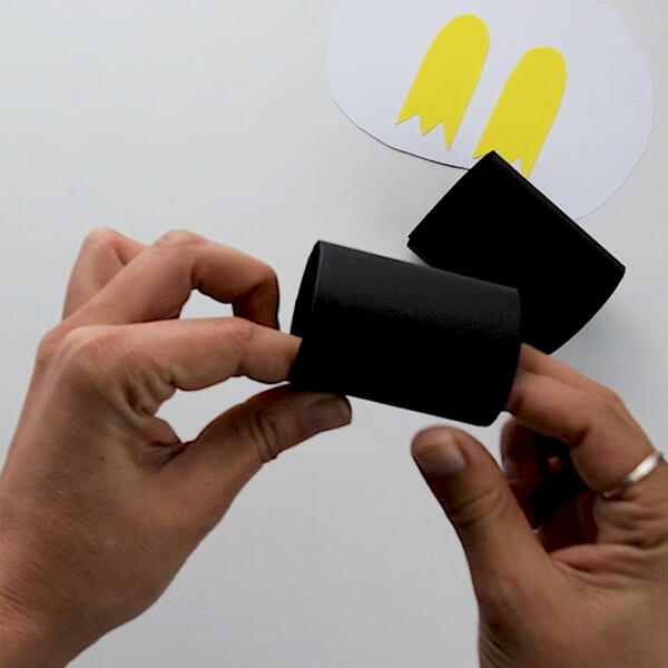 Rolling the glued black paper into a cylinder to form the base of the penguin’s body.