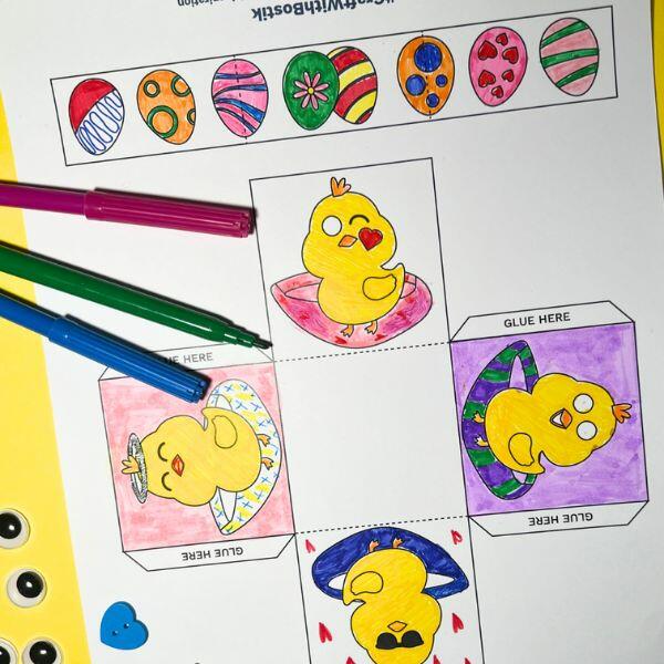 Partially coloured Easter basket template with bright markers and googly eyes placed nearby.