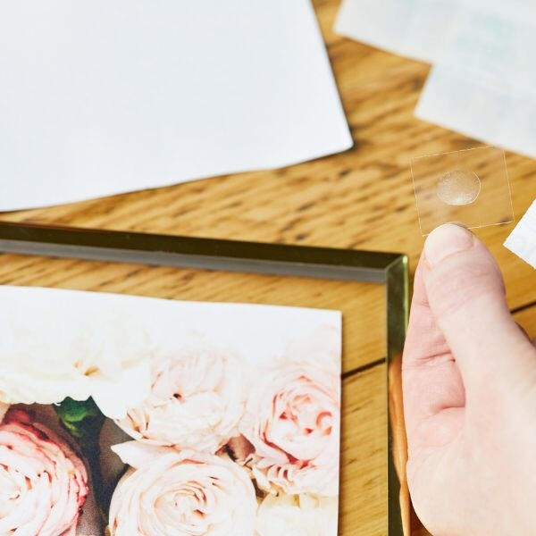 Transparent Glu Dot being applied to secure a photo print in a frame