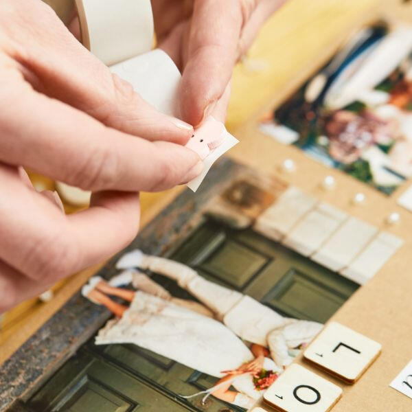 Peeling off a sticky dot to attach a wedding photo in a scrapbook layout