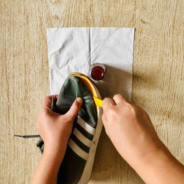 Applying Rugby adhesive carefully to the sneaker sole with a small applicator.