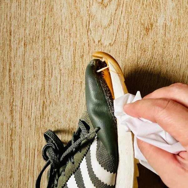 Cleaning the detached sole of the sneaker with a tissue before applying glue.
