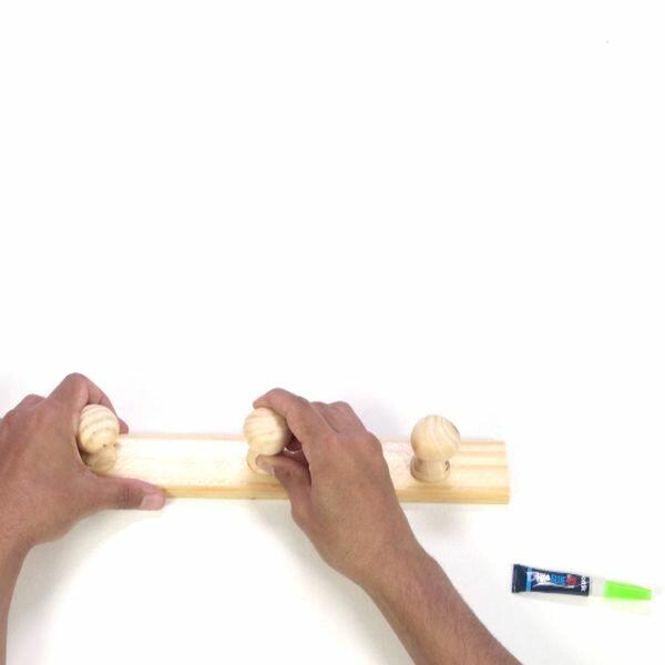 Hands pressing the repaired peg into place on the wooden rack, ensuring a secure hold.