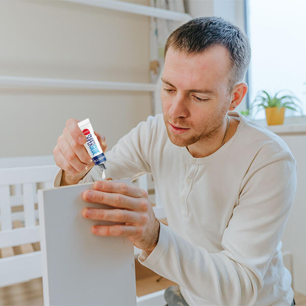 Man applying Bostik Super Glue Liquid to fix a wooden surface at home.