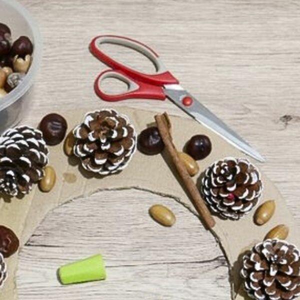 Finished Christmas wreath with pinecones, nuts, and berries displayed on a mirror for festive decoration.