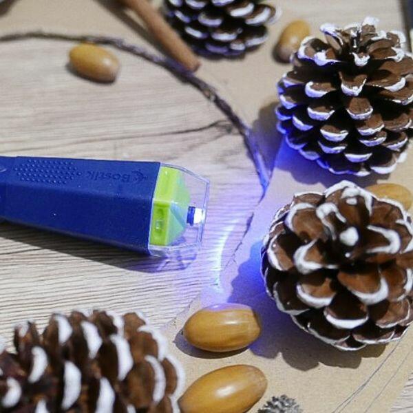 Gluing a chestnut onto a cardboard ring to create a Christmas wreath with pinecones, acorns, and natural accents.