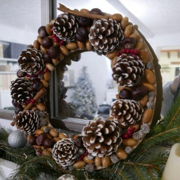 Finished Christmas wreath with pinecones, nuts, and berries displayed on a mirror for festive decoration.