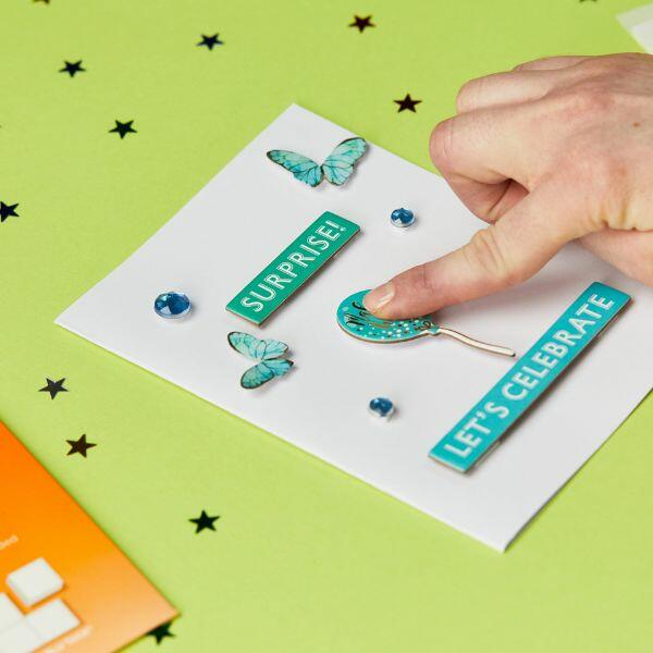 Adding raised decorations to a handmade card using Bostik Foam Pads.