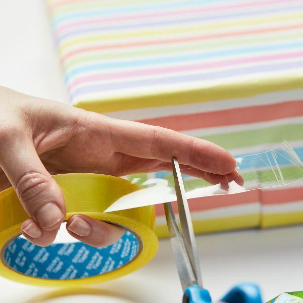 Cutting Bostik Sticky Tape from the roll while wrapping a striped present.