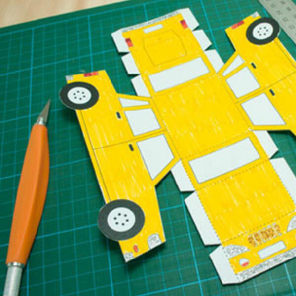 The yellow paper car partially folded along the edges, showing how the body of the car is starting to take shape.