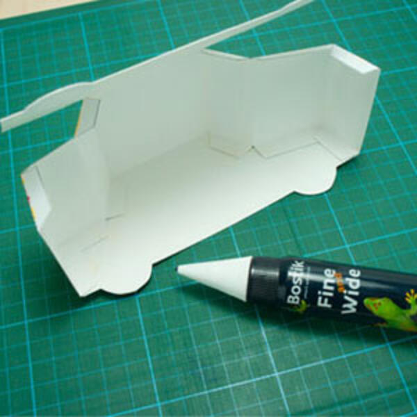 The yellow paper car fully folded and glued, with clear window panels and black wheels visible.