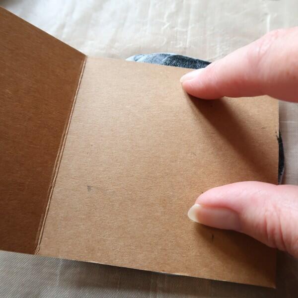 Hand pressing card onto Blu Tack stamp to transfer hare design.